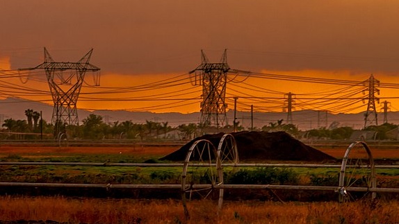Power lines against a glowing sunset sky